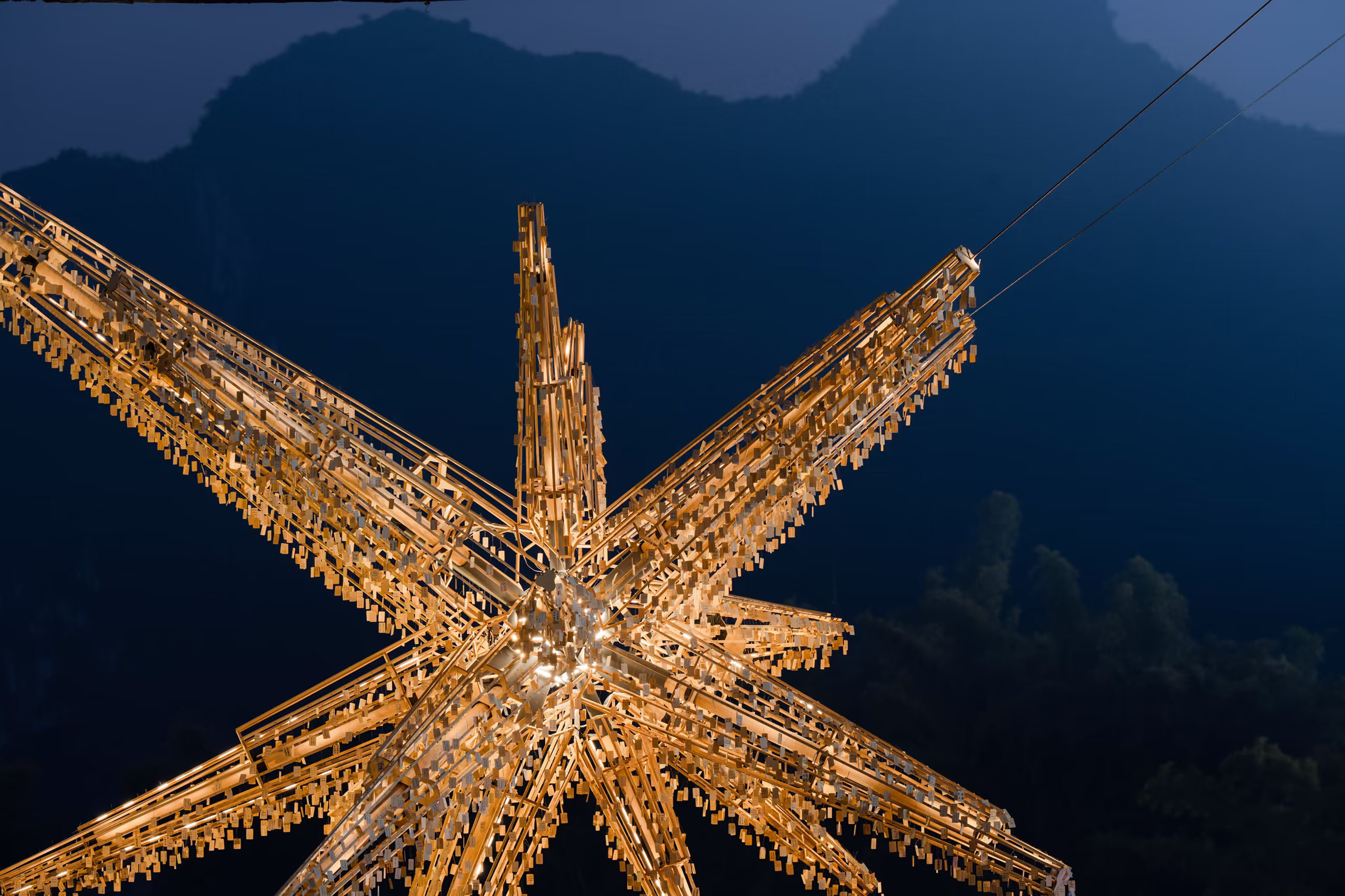 The illuminated "Super Star" installation at night, with wishing cards hanging on its timber frames
